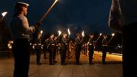 Soldaten stehen mit Fackeln in Formation auf dem Paradeplatz beim Großen Zapfenstreich 